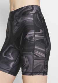 Černé a šedé mramorované šortky s vysokým pasem, plochými švy a hladkou texturou. Obsahují malé logo na boku.