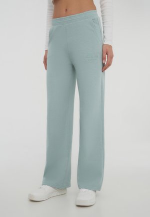 Pantaloni della tuta azzurri chiari realizzati in tessuto morbido, con una vestibilità ampia, cintura elastica e tasche laterali, caratterizzati da dettagli ricamati discreti.