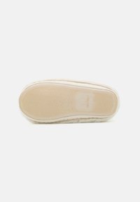Fuzzy beige slipper sole with a patterned light brown rubber base. Features rounded edges and a textured surface for traction.