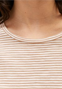 Pasiasty top w kolorze kremowym i jasnobrązowym, z okrągłym dekoltem. Miękka tkanina o gładkiej teksturze i równomiernych poziomych paskach.
