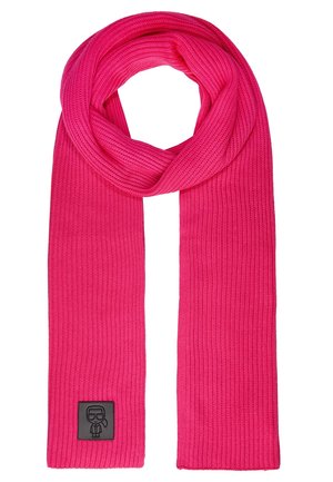 Kirkkaanpinkki neulottu huivi, jossa on ribbineulos, yläosassa lenkki. Huivissa on pieni musta merkki, jossa on tyylitelty henkilö, jolla on silmälasit ja solmio.