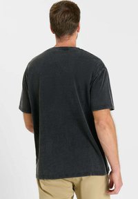 Donkergrijs katoenen T-shirt, korte mouwen, losse pasvorm, ronde halslijn, licht gebruikt uiterlijk, geen zichtbare patronen of accenten.