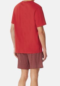 Camiseta de algodón roja de mangas cortas, combinada con pantalones cortos rojos estampados con un diseño geométrico y cintura elástica.