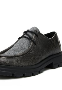 Chaussure noire en cuir avec une finition texturée, accent en feutre gris sur l'empeigne, bout arrondi et une épaisse semelle en caoutchouc noir robuste.