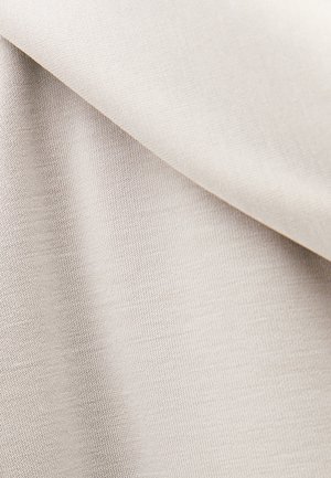 Light beige woven fabric folded diagonally, showing smooth texture and fine knit pattern in soft lighting.