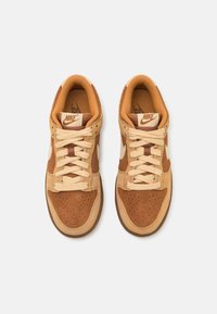 Nike Sneaker mit einem Obermaterial aus braunem Wildleder und Leder, beigen Schnüren, perforierter Zehenpartie und brauner Gummisohle. Signatur-Logo auf der Zunge.