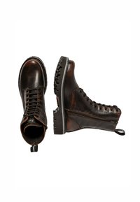 Bottes marron en cuir jusqu'à la cheville avec une finition texturée, semelles en caoutchouc noires et œillets en métal. Dotées d'une fermeture éclair sur le côté pour un enfilage facile.