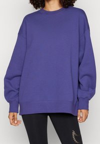 Sudadera oversized morada hecha de una tela suave, con cuello redondo, mangas largas y puños y dobladillo acanalados. Diseño simple sin patrones.