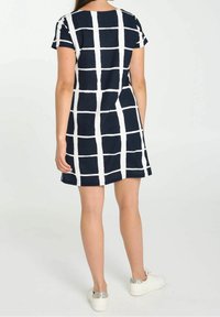 Námořnické a bílé bavlněné šaty s mřížkovaným vzorem, krátkými rukávy, kulatým výstřihem a rozšířenou siluetou, doplněné o bílé tenisky.