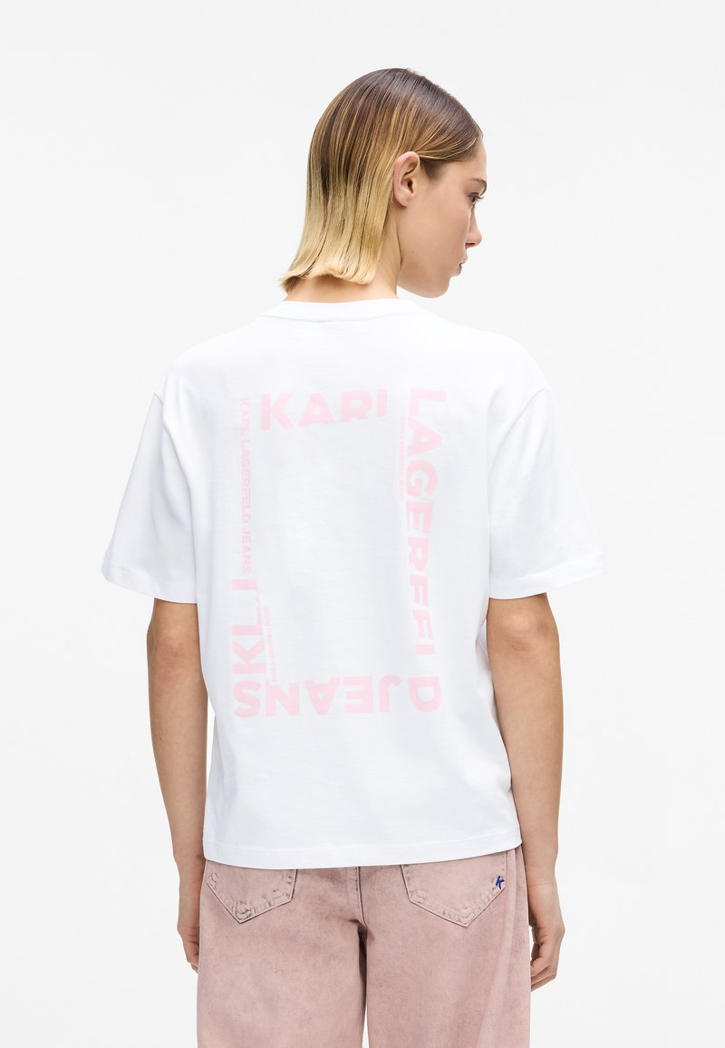 Valge puuvillane t-särk, millel on tagasiulatuvalt julged roosad bränditekstid. Lühikesed varrukad, ümara kaelusega, lõdvestunud lõige ja pehme tekstuur.