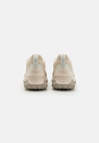 Sneakers beige da esterno con materiale testurizzato, tallone rinforzato e accenti grigio chiaro. Suola in gomma con battistrada per una migliore trazione.