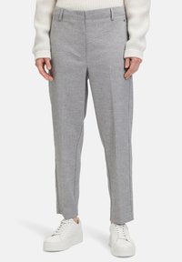 Grijze tailleurbroek met een gestructureerd patroon, voorzien van een aansluitende taille en rechte pijpen, gecombineerd met witte sneakers.