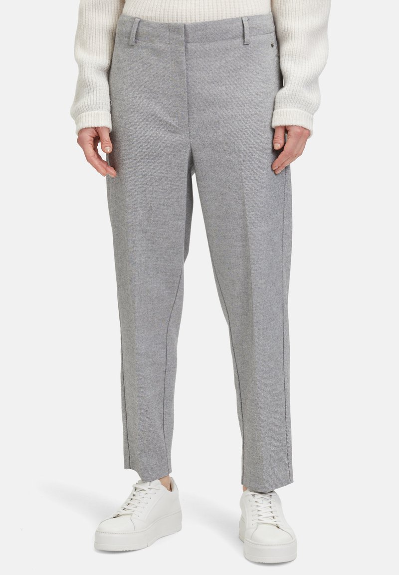 Grijze tailleurbroek met een gestructureerd patroon, voorzien van een aansluitende taille en rechte pijpen, gecombineerd met witte sneakers.