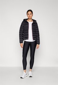 Mustat pitkätuntuvaiset takit, joissa on huppu, pinkit vetoketjut, yhdistettynä valkoiseen paitaan ja mustiin leggings-housuihin sekä valkoisiin urheilukenkihin.