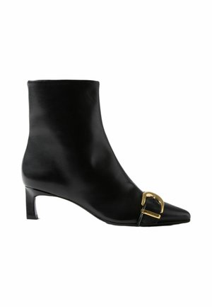 Bota de cuero negro para el tobillo con tacón bajo y detalle de hebilla dorada cerca de la puntera puntiaguda.