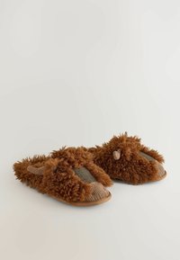 Brune slippers med fluffy tekstiloverdel, tekstureret ruskindstoe og vævede stofdetaljer. Har bløde pelslignende detaljer og en gummisål.