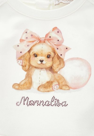 Il maglione bianco presenta un cane dei cartoni animati con un fiocco rosa, decorato con strass che riportano il nome "Monnalisa" sotto il design.
