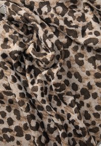 Tessuto a motivo leopardo in tonalità di marrone e beige, con una texture morbida e un design drappeggiato, caratterizzato da macchie di dimensioni e forme variabili.