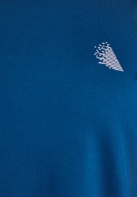 Blauwe katoenen T-shirt met een wit grafisch ontwerp dat lijkt op strepen of lijnen, gelegen aan de bovenlinkerzijde. Effen textuur.