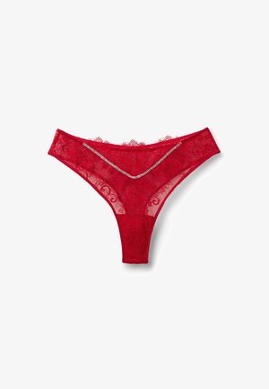 Tanga rojo de encaje con patrones florales, borde de encaje con diseño de ondas y un adorno plateado decorativo en la parte frontal. Material transparente y ligero.