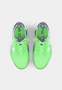 Neon green athletic shoes with a textured upper, gray accents, white stripes, and blue details. Features flat laces and a cushioned sole.