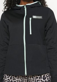 Svart zip-up hoodie med mintgrön foder och detaljer, med en logotypapplikation, justerbar huva och mjuk textur, designad för komfort.