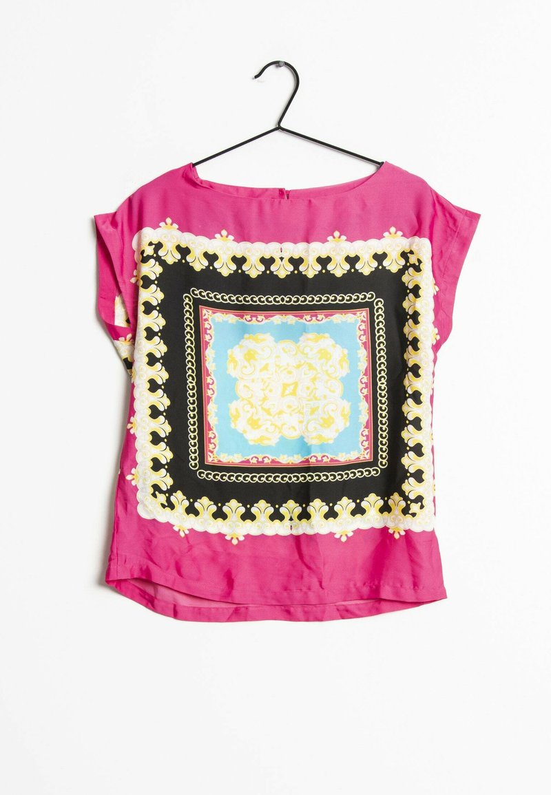 Blouse rose à manches courtes avec un motif carré coloré et orné, présentant des accents noirs, dorés et bleu clair. Tissu lisse et léger.