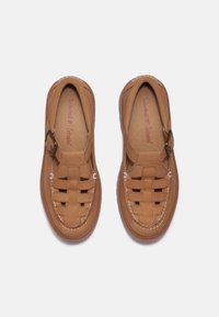 Sapatos slip-on de couro castanho com um design trançado, bico redondo e um acabamento com fivela lateral. Palmilha texturizada com o logótipo da marca.