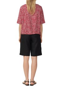 Rood en wit patroon T-shirt met korte mouwen, gecombineerd met zwarte shorts. De stof lijkt lichtgewicht en heeft een relaxte pasvorm.