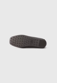 Black rubber shoe sole with circular grip patterns and a textured section at the heel; flat design with rounded toe.