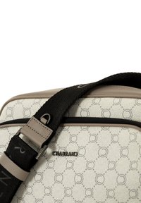 Borsa a tracolla beige con superficie decorata, presenta un logo, tracolla nera e dettagli marroni. Il materiale texturizzato migliora la presa.