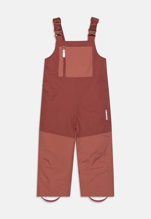 Dwukolorowe, wodoodporne spodnie ogrodniczki dla dzieci w kolorze rdzawego brązu, z regulowanymi szelkami na ramiona, przednią kieszenią na piersi zapinaną na zamek oraz elastycznymi paskami na stopy.