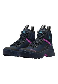 Nike ACG vandringskängor med en mörkblå textilöverkant, GORE-TEX-märkning, lila detaljer och en slitstark svart gummisula. Hög sko-design.