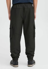 Svart cargo-bukser med elastisk midje, avsmalnende mansjetter, flere sidelommer og en jevn tekstur. Designet for komfort og funksjonalitet.