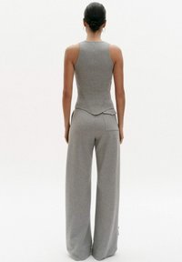 Grijs mouwloos topje en wijde broek, gemaakt van zachte, rekbare stof. Het topje heeft een aansluitend ontwerp; de broek heeft een achterzakdetail.