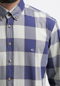 Camicia button-up con un motivo a scacchi blu e bianco, in cotone, con bottoni marroni e un piccolo logo ricamato sul petto.