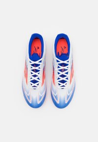 Scarpe da ginnastica bianche e blu con accenti arancioni. Le caratteristiche includono un design elegante, una superficie testurizzata e 12 occhielli con lacci bianchi.