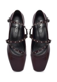 Talons en cuir verni bordeaux avec un bout carré, dotés de brides croisées ornées de clous en métal argenté et d'une semelle intérieure texturée noire.