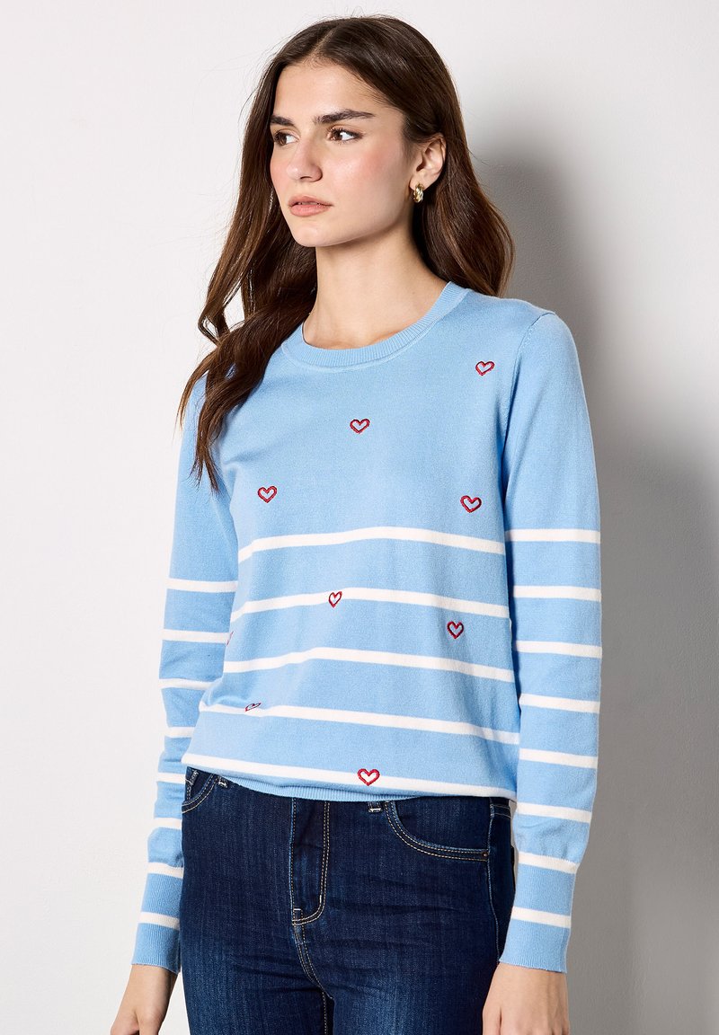Pull bleu clair avec des rayures horizontales blanches et de petits motifs en forme de cœur rouges. Il comporte un col rond et des manches longues.