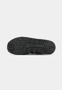 Semelle de chaussure noire avec motifs géométriques et logo "diadora" centré sur un fond clair uni.