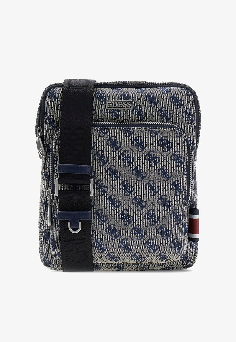 Sac bandoulière carré en tissu à motifs bleus, poche zippée devant, logo Guess, large bandoulière noire et détail de bande latérale rouge-blanc-bleu.