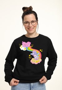 Sudadera negra con un gráfico colorido de dos osos de dibujos animados en nubes, con un arcoíris y estrellas. Tejido suave, diseño de cuello redondo.