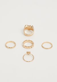 Set of six gold rings featuring various designs: a smooth band, a textured band, and a chunky ring with a unique shape and accents.