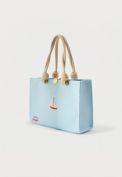 Τσάντα ώμου ανοιχτού γαλάζιου χρώματος με μπεζ χοντρά κορδόνια ως λαβές, ροζ κέντημα ιστιοφόρου και κόκκινο κείμενο «Louise Pretzel» στην κάτω αριστερή γωνία.