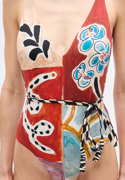 Μαγιό με βαθύ ντεκολτέ σε σχήμα V, πολύχρωμα αφηρημένα λουλουδάτα και γεωμετρικά σχέδια, και ζώνη με ασπρόμαυρες ρίγες δεμένη στη μέση.