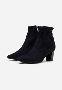 Botas de tobillo de ante azul marino con punta afilada, cierre de cremallera y tacón grueso. Presentan detalles cosidos a lo largo de los lados.