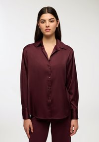 Burgundowa jedwabna koszula z kołnierzykiem, długimi rękawami i guzikami z przodu. Gładka tekstura i luźny krój, uzupełniający pasujące spodnie.