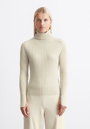 Beige ribbed turtleneck sweater with long sleeves and a fitted design, made from a soft knit material. Features a high collar and subtle stitching.