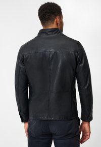 Svart läderjacka med en slät yta, med ståkrage, strukturerade sömmar och en skräddarsydd passform, sedd bakifrån.