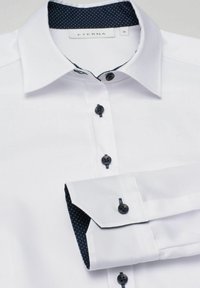 Witte dress shirt met zwarte knopen, voorzien van een marineblauwe polka dot binnenkraag en mouwaccenten. De stof heeft een gladde textuur. Maat 36.